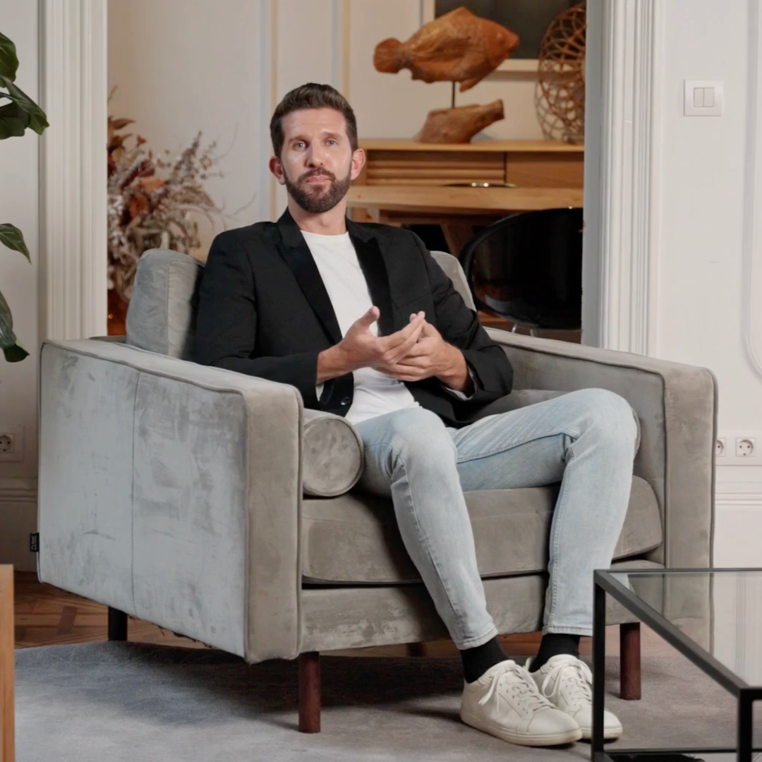 Man sitting on a gray armchair in a stylish living room with decor elements.