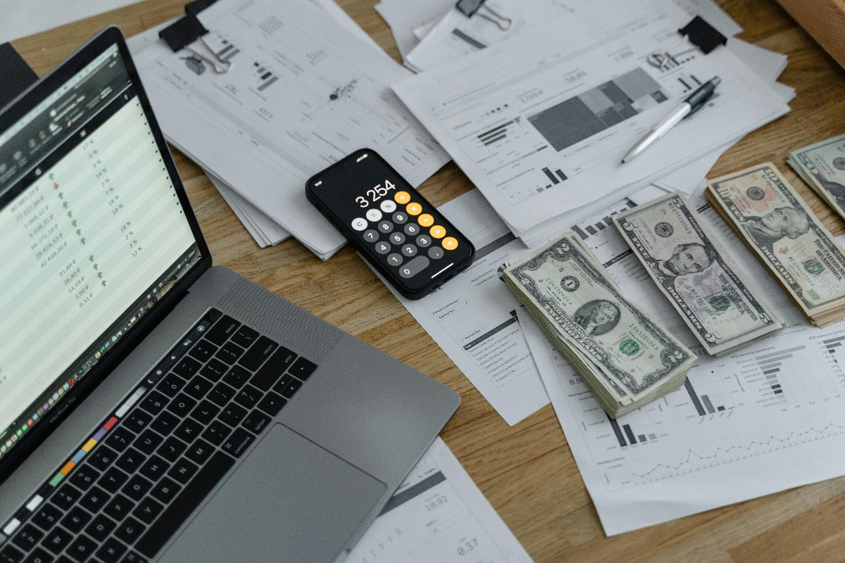 Laptop, calculator, and money on a desk with financial documents